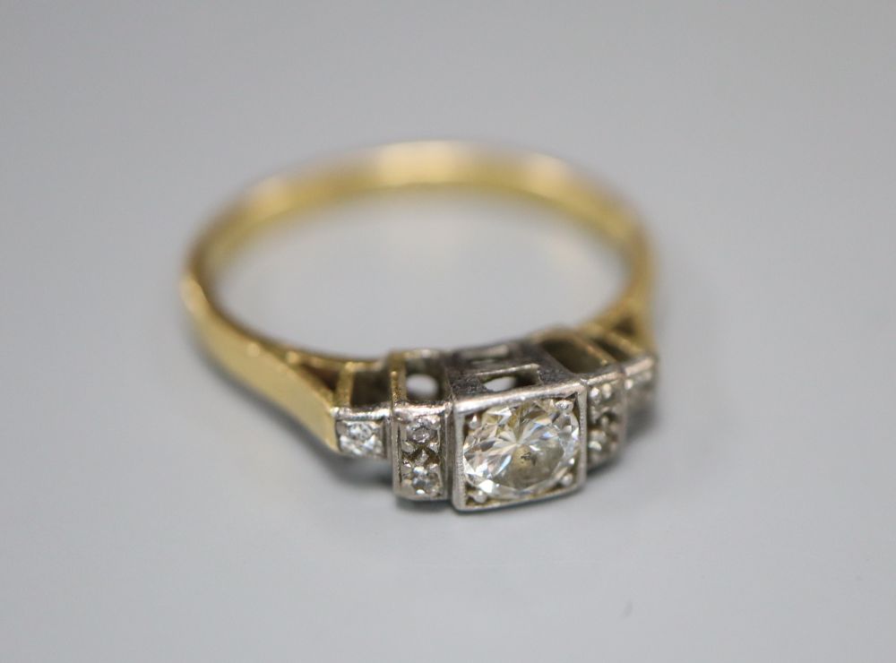 An 18ct and plat diamond ring, the square set central stone flanked each side by three further diamonds, size N, gross 3 grams.